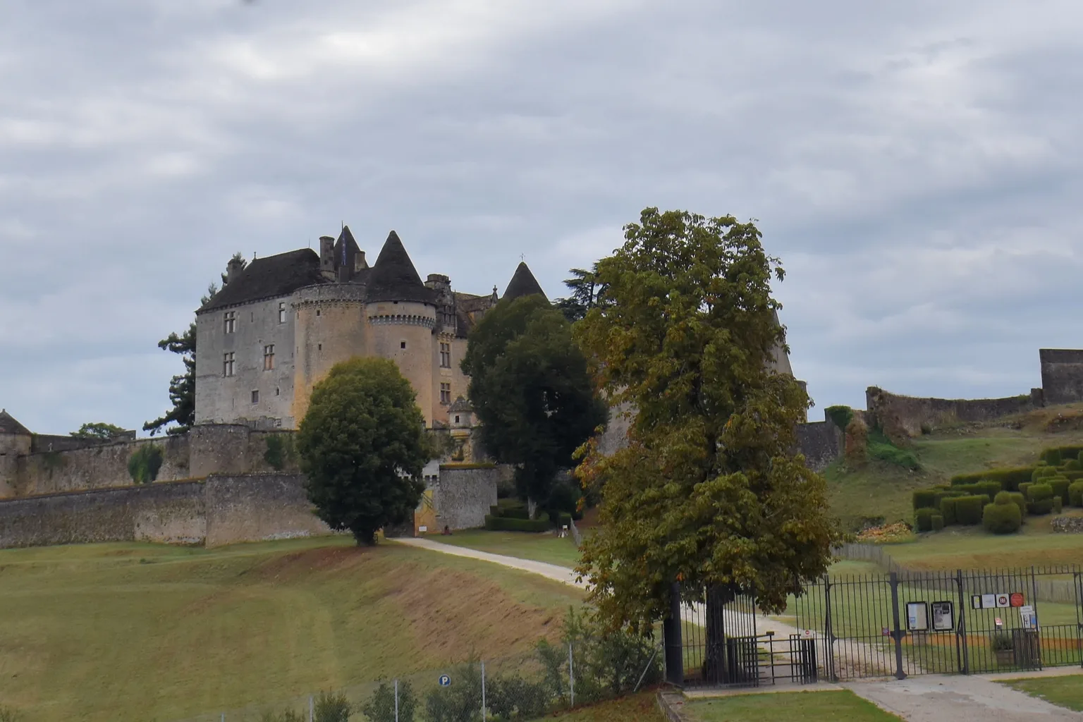 Vue sur le château de Fénelon depuis l'ouest, ses tours rondes se dressant au-dessus de la forêt